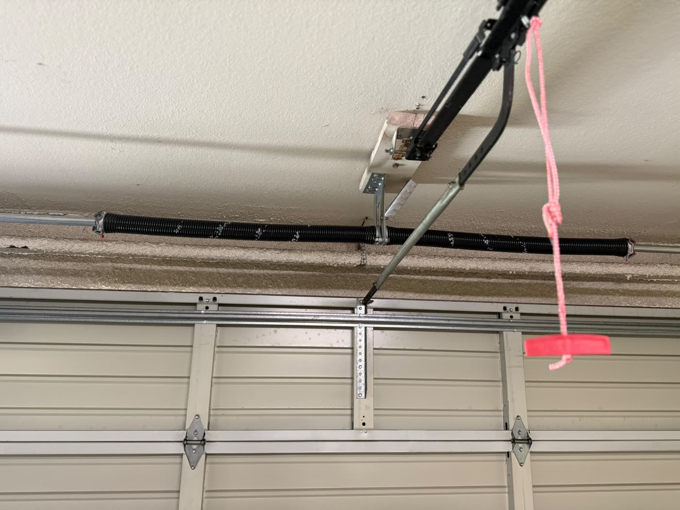 New torsion spring and opener rail installed above a garage door