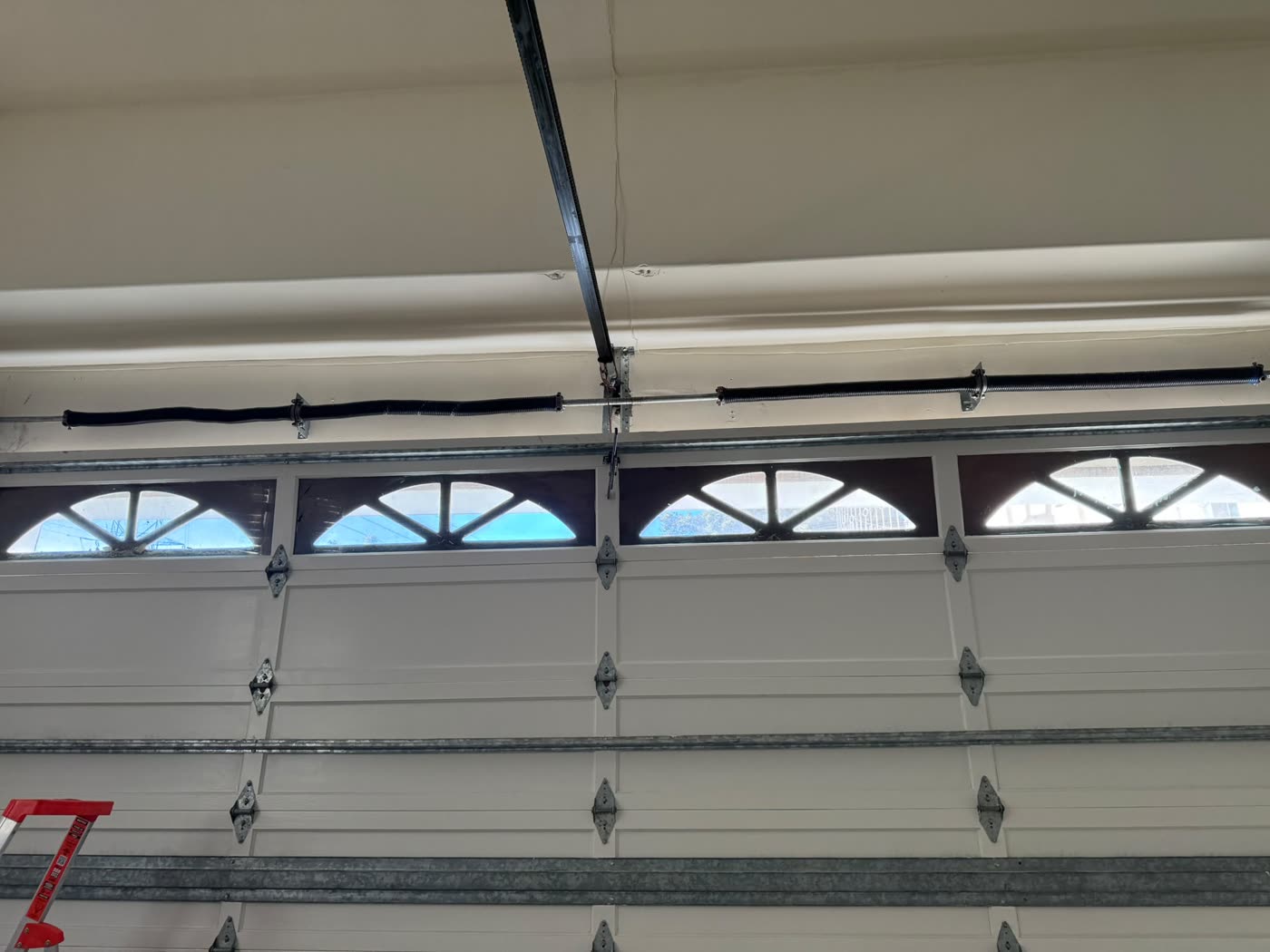 New torsion springs mounted above a white garage door with arched windows